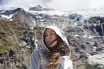 Young woman stands in front of a glacier in New Zealand. by Vermont photographer Judd Lamphere