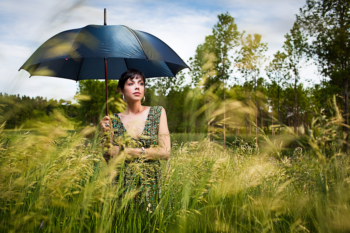 Vermont photographer Monica Donovan shoots a portrait of Rose with an umbrella in a grassy field at Shelburne Farms