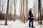 Bassist Aram Bedrosian poses with his guitar in the snowy woods in Shelburne, Vermont.