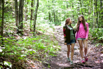 Two young women walk in the woods of Maine. by Vermont photographers at Reciprocity Studio, Burlington