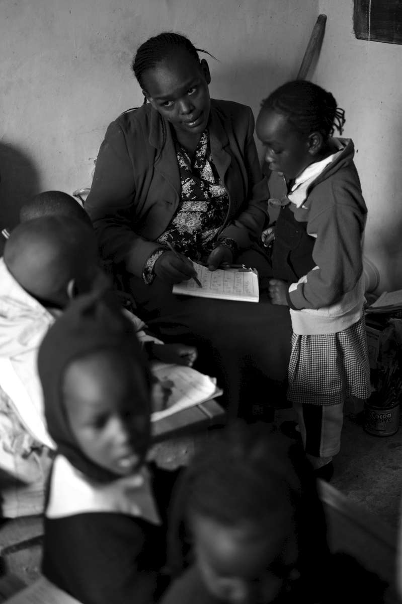 While testing a student's reading ability, nursery teacher Cecilia Muringi eyes a student who is not behaving properly.