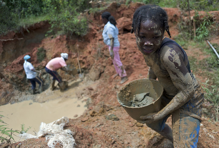 A young girl toils at a small-scale gold mining site along with members of her family.