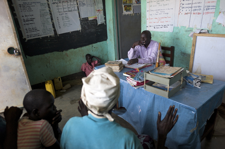 Alex Opira, right, headmaster at Acutomer Primary School, tries to resolve a problem about overpaid school fees involving Pauline Akwero, foreground, her Robert Mugisha, 11, seated on the floor - far left, and a teacher.
