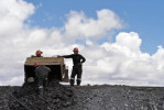 Miners dump a container of ore that has been examined for gold. 