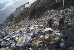 Gold miners leaving the mountains make their way through a pathway of garbage. The horrendous sanitary conditions result from the unregulated disposal of garbage and human waste. 