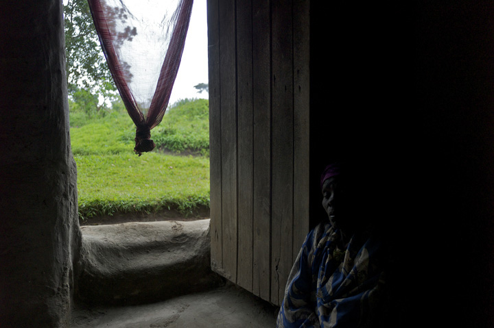 Imelda Gafabusa, 70, falls asleep near her front door while waiting for a rainstorm to end; before the rain she spent four hours working in the field tending to her sweet potato, cassava, and groundnut crops. 