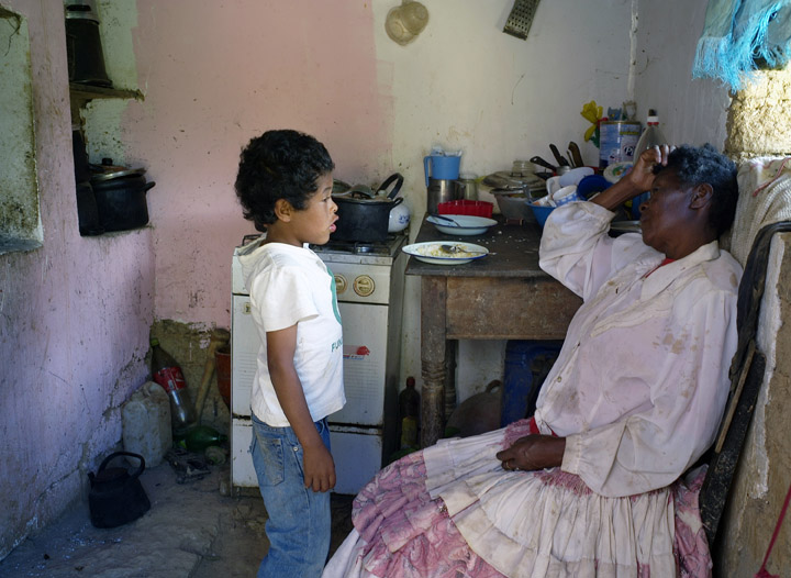 Exhausted from picking coca leaves Juana Vasquez, 71, chats with her 7-year old grandson after preparing his lunch.