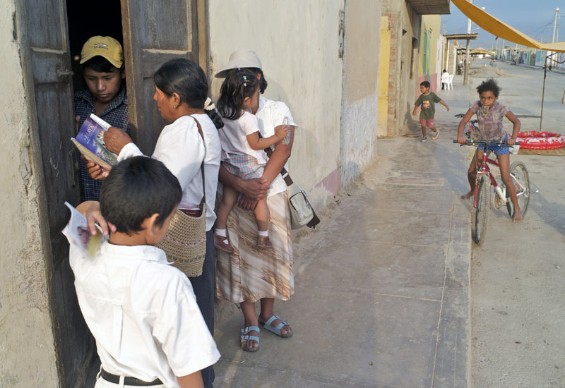 An Afro-Peruvian girl, right, watches as two evangelical women, with children, go door-to-door distributing religious material.
