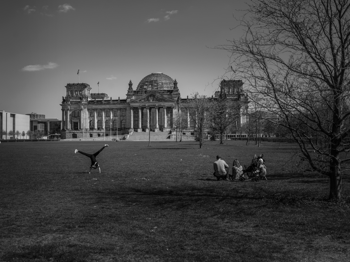 April 17, 2020 - Berlin, Germany: A family relaxes in front of the Reichstag (German Parliament) and  kids do cartwheels during the coronavirus pandemic.  As the rate of new infections nationwide continues to slow, the German government is seeking to establish and implement a roadmap for easing restrictions on public life and the impact  the virus is having on the economy. So far there are over 130,000 cases of confirmed infections of Covid 19 in Germany, over 3,000 people have died and about 57,000 people recovered. 
