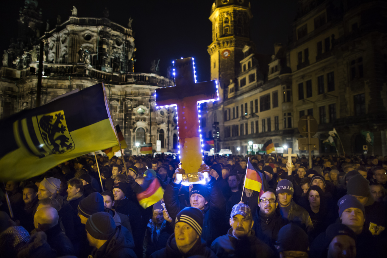 December 22, 2014 -Germany,  Saxony, Dresden :  A demonstrator holds a illuminated cross as he takes part in the demonstration of about 17500 Supporters of the Pegida movement  at another of their weekly gatherings. Demonstrators shout slogans as: 'Luegenpresse' (Mendacious Press) and 'Wir sind das Volk (We are the people' the 1989 slogan of the GDR's peacefull freedom demonstrations). 'Pegida is an acronym for 'Patriotische Europaeer Gegen die Islamisierung des Abendlandes,' which translates to 'Patriotic Europeans Against the Islamification of the Occident' and has quickly gained a spreading mass appeal by demanding a more restrictive policy on Germany's acceptance of foreign refugees and asylum seekers. Parts of this  right-wing movement is also against the Euro and the Western liberal style of living in general. The first Pegida march took place in Dresden in October and has since attracted thousands of participants to its weekly gatherings that have also begun spreading to other cities in Germany. (Hermann BredehorstPolaris)