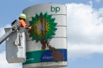 A worker cleans a vandalized BP sign at a gas station in 2nd Avenue in Harlem