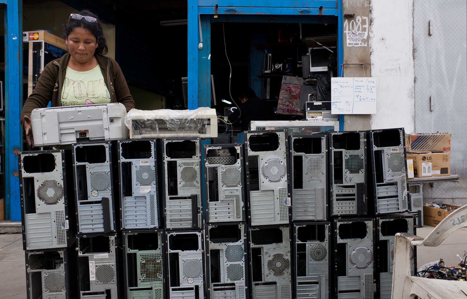 Senora Dona prepares PCs for sale on the sidewalk in front of the electronics repair shop, where she works. 