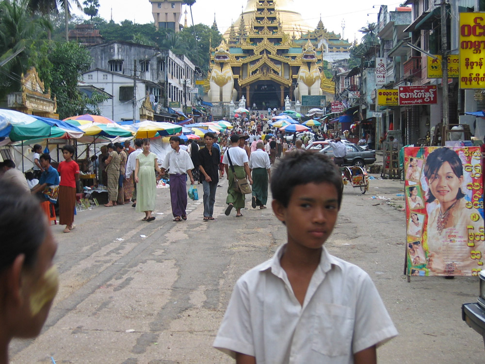 Local boy stands amidst people running errands outside the Shwedagon Pagoda. 