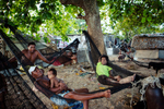 Men relax during the heat of the day on hammocks. People are most active around dawn and dusk when the temperature cools. Bairiki Village, Tarawa Island, Kiribati.