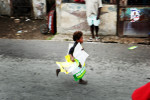 Small child runs away with Celestin Posters during political manifestation in the streets of Cite Soleil. Haiti's most impoverished slum.