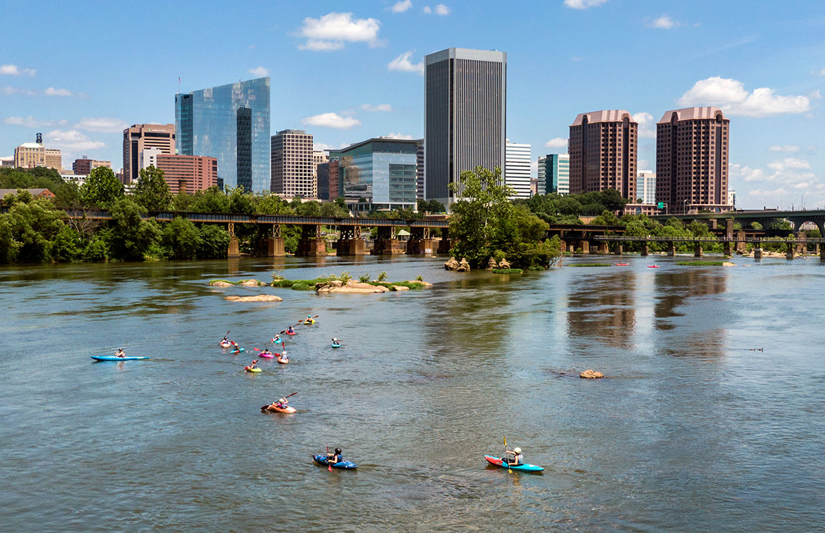 Summer campers of Passage Adventure Camp learn kayaking on James River as downtown Richmond is shown on the background in Richmond, Virginia.