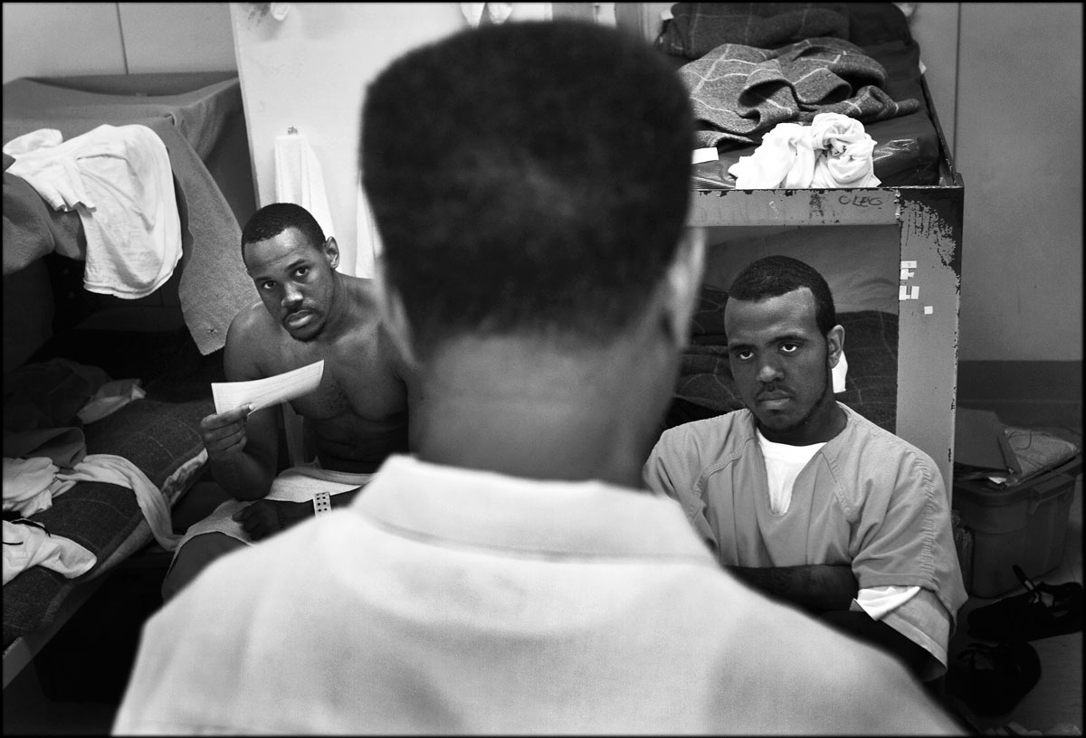 Michael Vanhook, left, and Thaddous Kelly, right, inmates, listen to James Robinson, who visits the jail as a chaplain to spread words of Jesus. Robinson has been reaching Southeast area, where city's poorest and most crime-ridden community, with his ministry for 16 years as a street minister and a chaplain for the city jail.