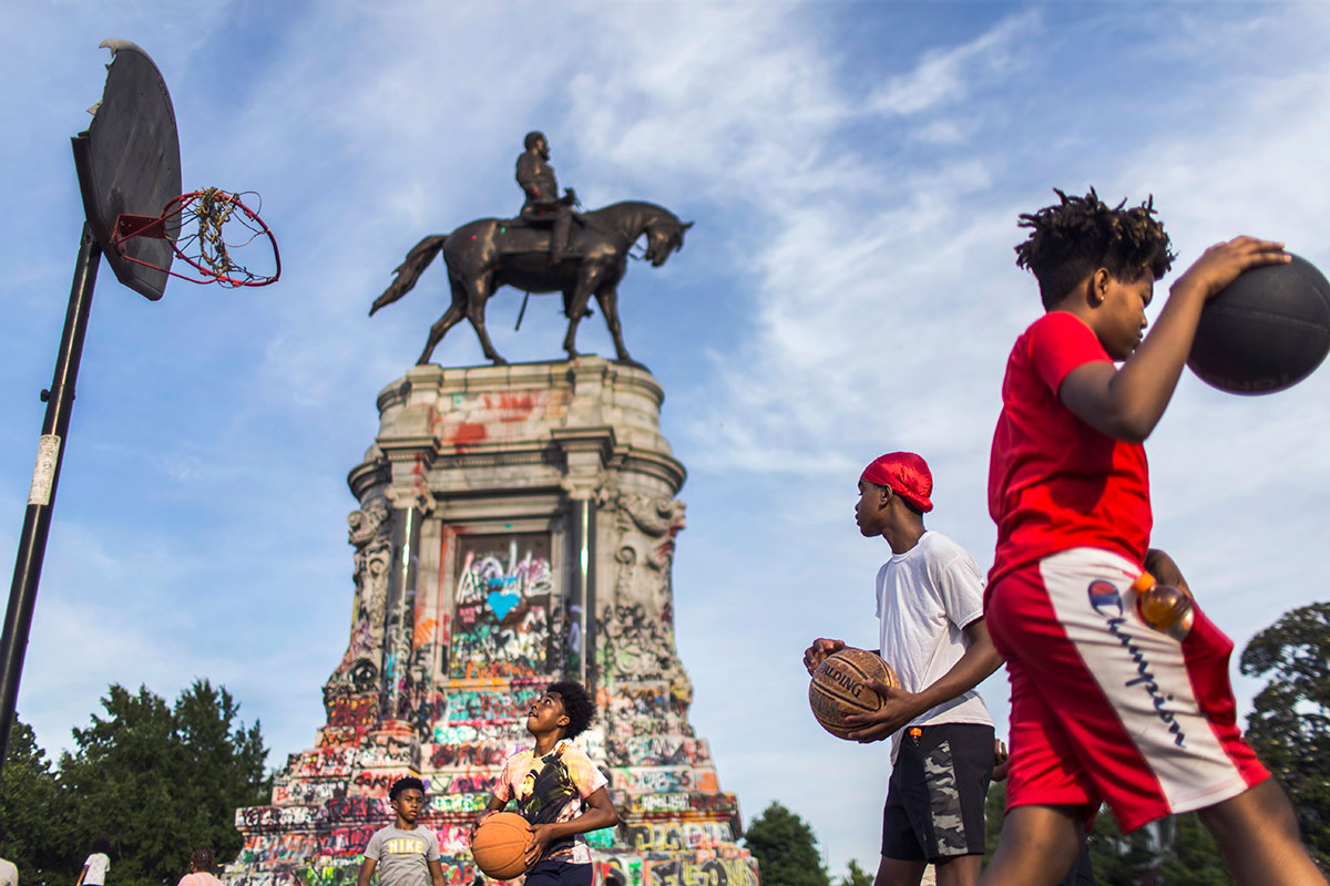 From center to right, Amar Bullock, 13, Zykuan Williams, 13, and Anthony Rosser, 12, play basketball near the sigh of Marcus-David Peters Circle at Robert E. Lee monument.