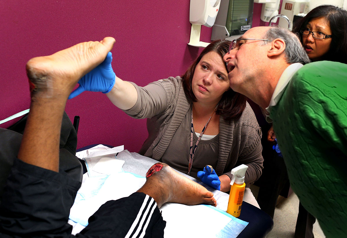 Open wounds on Edward's feet are examined by Kim Curran, center, a registered nurse and care coordinator, Dr. Mark Solomon, a plastic surgeon, and Dr. Connie Domingo, a pediatric physical medicine & rehabilitation physician, at Shriners Hospitals for Children in Philadelphia. Edward's feet have opened wounds by pressure from his bones as gunshots paralyzed Edward from the waist down. After doctors’ concern of the infection, Edward has to stay at the hospital until he finds proper open wound cares back home in Richmond. 