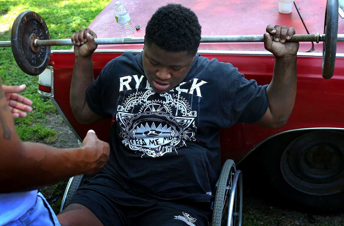 Edward exercises with the help of Rodney Debro, a neighbor, at Debro's backyard in Richmond. To prepare his spinal fusion surgery, Edward tried to lose his weight and build the muscle.