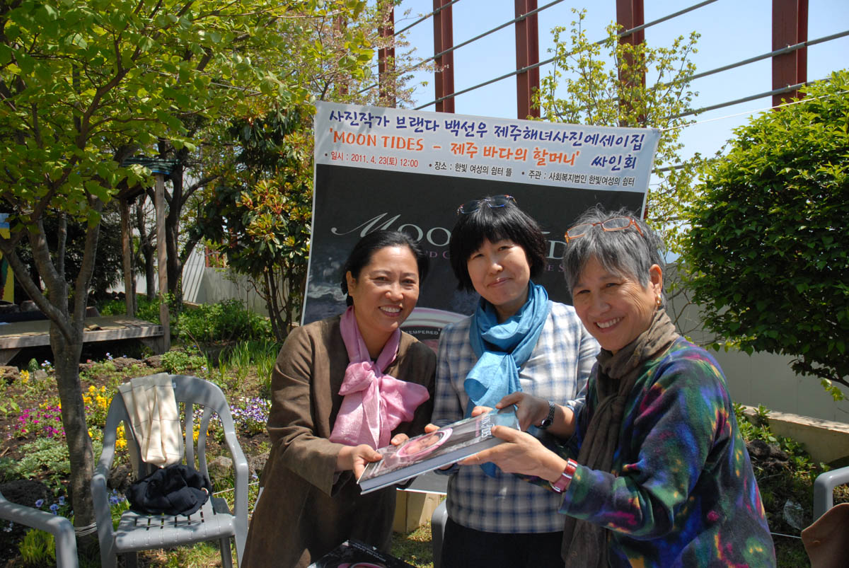 Left: Kang Mi-kyoung, director of Hanbit Shelter for Women, receives copy of {quote}Moon Tides--Jeju Island Grannies of the Sea.{quote} Middle: Han Young-sook, translator and interpreter. Right: Author