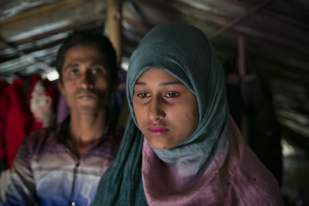 Rahul Amin, 20, and Sabakur Nahar, 15, pose for a photo in Cox's Bazar, Bangladesh. They were married two months ago in a Bangladesh refugee camp. Rahul is from Tula Toli and Sabakur is from Bouli Bazar. They both fled to Bangladesh after the August 25th attack. Rahul lost 20 relatives in the attack and spent days walking to Bangladesh, hiding in the forest and drinking water from the paddy fields along the way. Sabakur saw her father killed by the military and lost 6 relatives during the attack. She got separated from the rest of her family and spent 8 days walking to Bangladesh. Sabakur and Rahul met in Bangladesh at the Kutupalong transit center. He says that he thought she was beautiful so he approached her and they started talking. After 3 days he proposed marriage to her. She told him yes, but that she couldn't marry him until she found her family. Eventually she gave up hope and they were married a few days later. A few weeks after that she located her family in a camp. Rahul says 'Her age didn't matter to me, her body structure isn't young and small, she looks older, so it's okay. In our culture, women who look older have to get married. If other people see her they'll criticize her family, saying your daughter is getting older she needs to get married now. In Islam, any girl who looks older and is seen outside of the house, it's bad for her family. In the Koran, it says that if anyone sees a girl outside of the house, she will be cursed.' Sabakur says 'I wanted to wait until I was 18 to get married, 15 is too young. I agreed because I didn't have my family here. If I was in Myanmar I never would have agreed to get married. I was all alone here, so I agreed.'