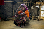 Jamalida Begum is seen in her makeshift house that she shares with 6 other refugees on in Kutalong Rohingya refugee camp in Cox's Bazar, Bangladesh. Jamalida Begum came to Bangladesh 15 days ago from Hadgudgapara village in Myanmar. 2 months ago the military came to her village, killed her husband and burned her home to the ground with everything she owned in it. The next morning the military surrounded her village. {quote}They dragged me and the other women to the yard and beat us. I was screaming and begging Allah to save me. The military screamed {quote}Where is your Allah now? He's not saving you!””  3 men dragged her to the bush, pointed a gun at her and said ”If you resist, I'll shoot you” then took turns raping her until she lost consciousness. A few weeks after the rape, a group of foreign journalists came to her village and interviewed Jamalida and other rape victims. That night the military came to her village and cut the throat of the man who helped translate for the journalists. The soldiers went door to door with Jamalida’s photo looking for her, and neighbors ran to warn her. She ran away and for 5 days she took shelter in the bush and in different houses until she fled to Bangladesh. She says that every night she has nightmares about the Myanmar military. {quote}I have flashbacks when I hear loud noises. I've heard that the military has made big posters of my photo and they're still going door to door looking for me. I'll never be able to go back. If I go back, they'll kill me. I will never go back. Sometimes I'm scared that they'll find me here.{quote} 