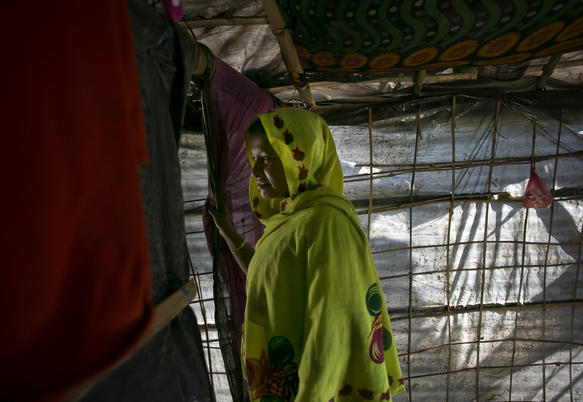 Nojiba is seen in her makeshift house that she shares with 14 other refugees in Kutalong Rohingya refugee camp in Cox's Bazar, Bangladesh. Nojiba came to Bangladesh 2 months ago from Delpara village in Myanmar. She describes a happy life living in Myanmar until 3 months ago when the military suddenly started coming to her village, beating, killing and harassing people. {quote}I felt scared, I prayed and read the Koran, hoping to feel better. I lived in a constant state of fear.{quote} Nojiba says {quote}The day before I fled to Bangladesh the military came again to our village. They found the place in the bush where I was hiding with other women and girls. They took the young girls into nearby houses and beat and raped them. I could hear their screams. One soldier put a gun to my head and said {quote}Let's go{quote}. I started screaming and fighting back and 3 men dragged me to a room in a nearby house. They held a gun to my head and two soldiers took turns raping me for an hour.{quote} The next day she and her family decided it was time to flee to Bangladesh. They had to walk all day to the Naf river that separates Myanmar from Bangladesh. {quote}My whole body hurt. I thought that I couldn't keep walking, I felt weak.{quote} They paid a boatman to help them cross the river and they finally made it to Kutapalong refugee camp in Bangladesh. {quote}We don't have enough to eat here, but at least we can sleep well and it's safe enough that my children can leave the house.{quote} She has been getting mental health counseling from Doctors Without Border and says that {quote}I want to move past my sorrows.{quote} 