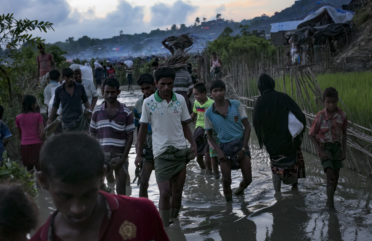  Refugees walk through a muddy path in the Unchiprang Rohingya refugee camp 