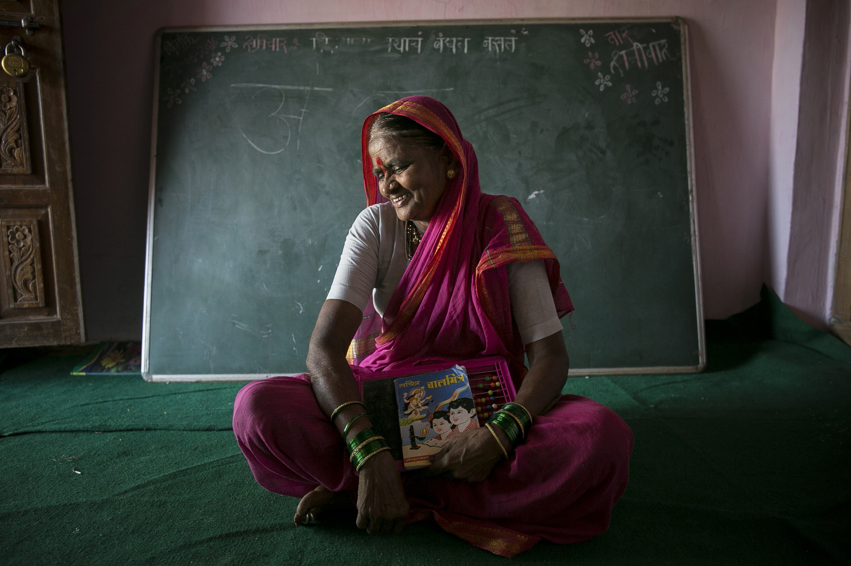 70 year old Nirmalabai Sakaram Kedar poses for a photo in her school. She was married at the age of 9, to a 25 year old man, and was sent to live with him when she turned 16. and never had the opportunity to go to school until now.There are 30 elderly women between 60 and 90 years old who are going to school for the first time in their life at the Aajibaichi Shala or the Grandmothers’ School, in Phangane village of Thane district, India. Most of them were deprived of a formal education as a child. Their families were either too poor to afford their education or they simply thought “it was sheer waste of time and money to invest in a girl child’s studies”. The common perception was that the girls, many of whom would be married off while they were underage, were destined to do the household chores only. The school, which started on the International Women’s Day this March, aims to empower the elderly women and break the stereotypes.