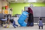 Rohingya refugee 23 year old Sakinah cleans up after English classes while her children 4 year old Shafi Rukh Khan and 1 year old Nur Sharifah play at the Rohingya Cultural Center of Chicago 