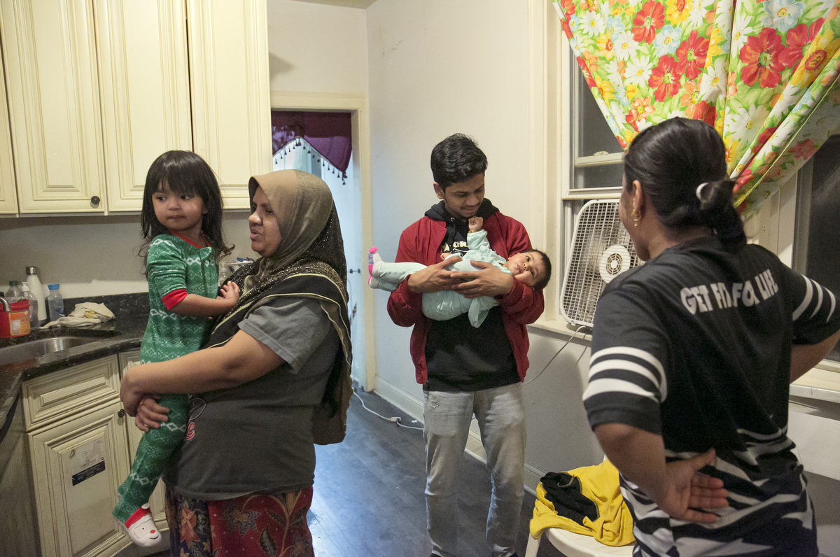 25 year old Maimunah Shukor holds her daughter, 3 year old Norfarzana while her siblings chat in the kitchen on January 12, 2019 in Chicago, Illinois. The Shukor family arrived in Chicago in 2014 from Malaysia. Mohammad Shukor fled Myanmar in 1978 after the military shot him and arrested his father, who died in jail. He fled to Thailand by boat and spent 5 years there before making his way to Malaysia with his family. In Malaysia he and his family were denied an education, had to work illegally, and were frequently arrested and harassed by authorities. When he and his family were resettled in the US he says he {quote}felt so happy to finally have a country, to finally have a place to call home{quote}. 