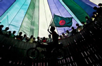 A man holds a Bangladesh flag as he rides a motorbike in a {quote}wheel of death{quote} at a circus in Bangladesh.