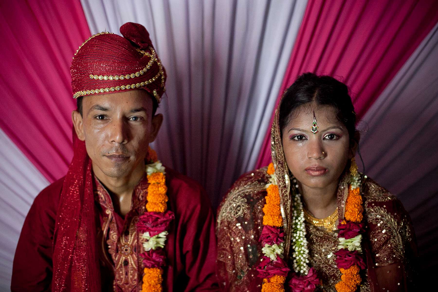 13 year old Runa Akhter sits next to her husband, 29 year old Zahrul Haque Kajal, the day of her wedding in Manikganj, Bangladesh. Runa was in the 7th grade, and loved reading, sports and traveling. She wanted to wait until she was 21 to get married but, {quote}No boy want's to marry a girl older than 18 in my village{quote} she said. 