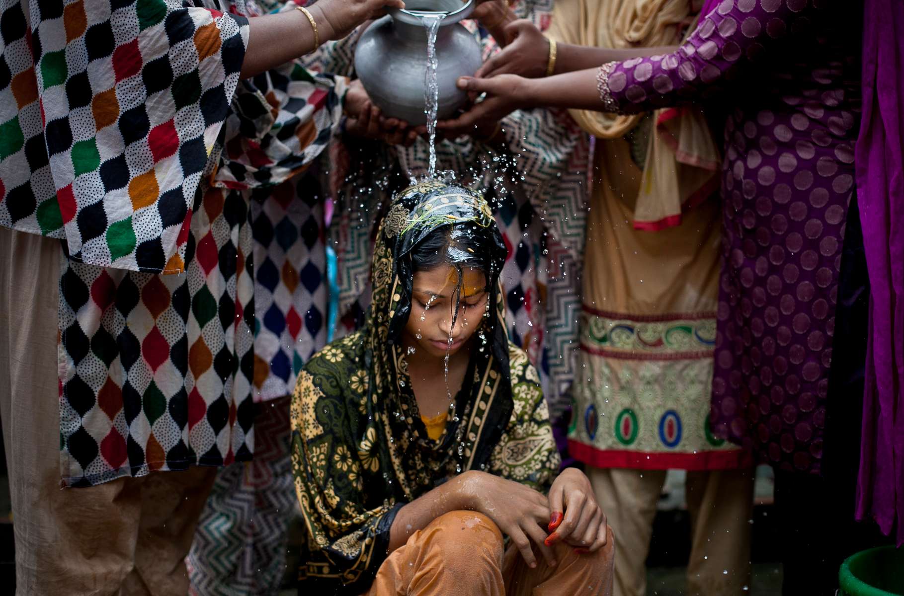 5 year old Nasoin Akhter is bathed on the day of her wedding to a 32 year old man in Manikganj, Bangladesh.