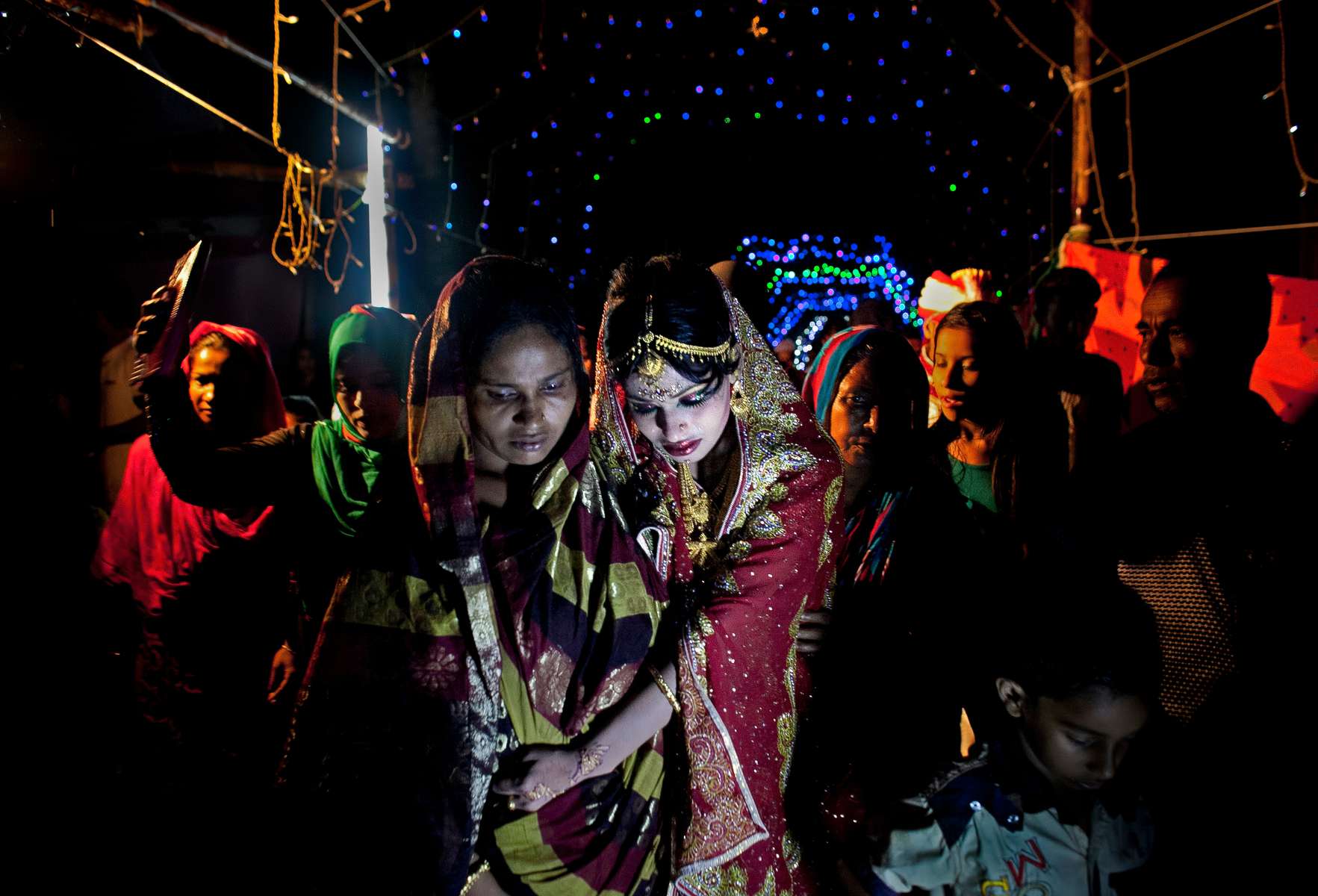 15 year old Nasoin Akhter is led by relatives to a car that will take her to her new home on the day of her wedding to a 32 year old man in Manikganj, Bangladesh. 