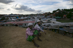 Men sit on a hill at a Rohingya refugee camp  
