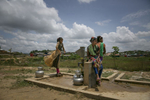 Girls pump water from a well in the camp