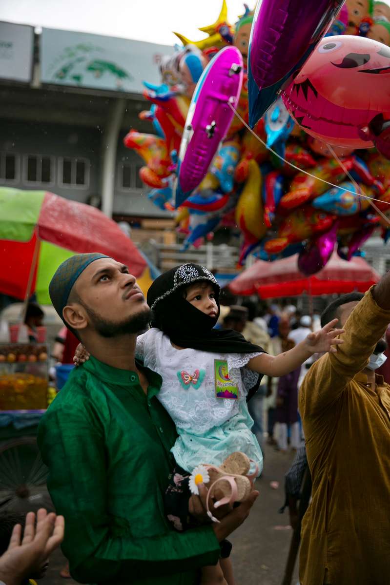 A man and his child look at balloons a vendor is selling outside mosque on Eid day in Dhaka, Bangladesh.