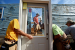 Habitat for Humanity volunteer Jonathan Browning, center, of Amherst, is seen through the window of a door being installed in one of two homes volunteers worked to construct Saturday during a Habitat for Humanity 'Blitz Build' in Altavista.  (Photo by Max Oden/The News & Advance)
