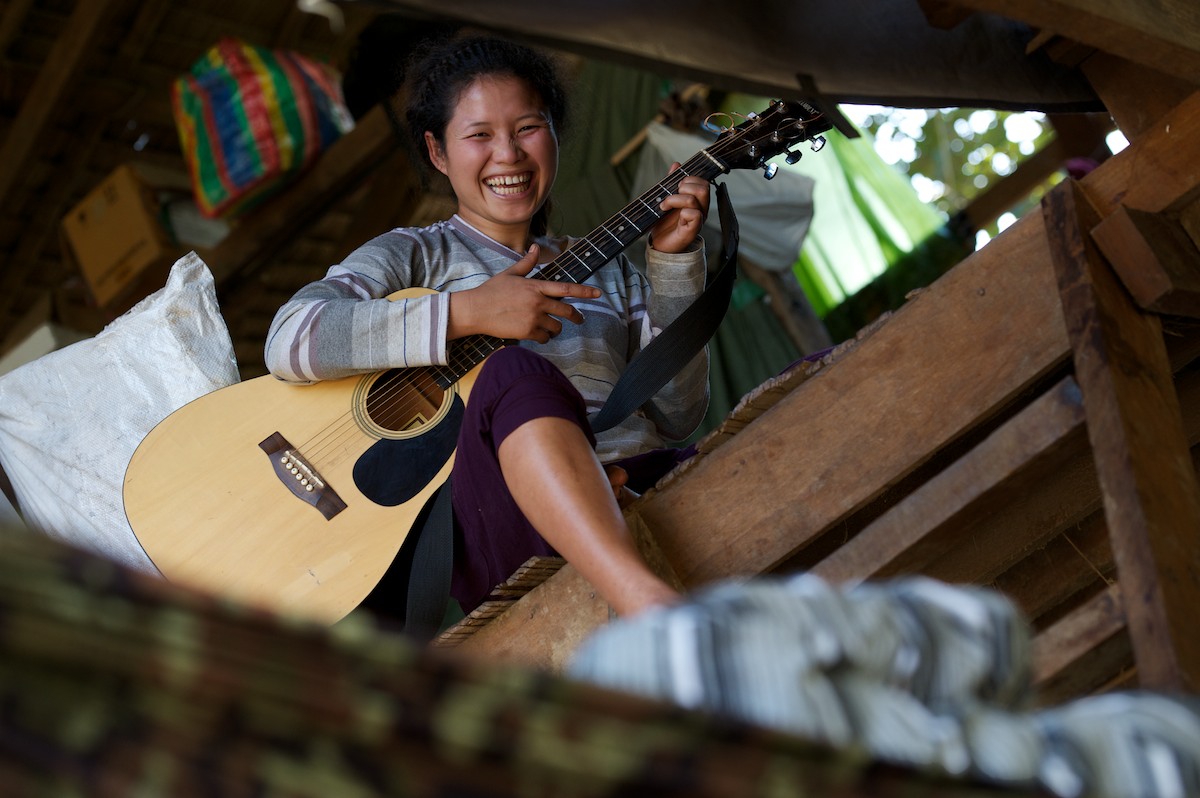 Naw Paw Khu Htee, a medical student at the Free Burma Ranger's Jungle School of Medicine, takes a break from her studies and practices guitar in the women's dormitory. 
