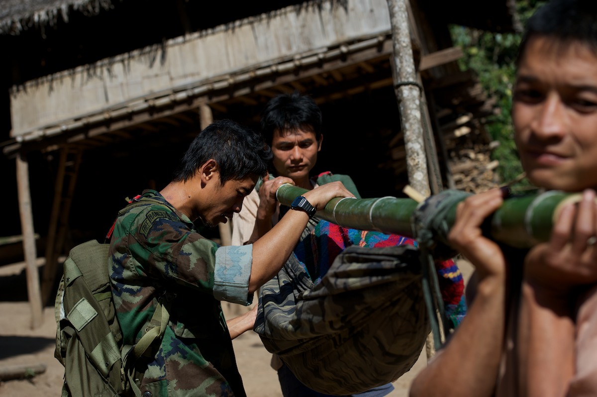 Toh, a medic with the Free Burma Rangers and staff member of the Jungle School of Medicine, prays for a patient while out on a field mission. Villagers use a bamboo hammock stretcher to carry a young girl who has a severe case of staff infection to the JSMK clinic two hours away. This patient was diagnosed with a severe case of staff infection in her left shoulder and left hip, a life threatening infection that was successfully operated on. 