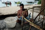 Mr. Korn, a local Urak Lawoi', trap fisherman constructs a small fish trap made out of rattan, steel wire and plastic. Trap fishing is practiced in the Adang Archipelago's near shore coral reef and rock environments at average depths of 10m to 20m. 