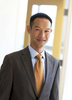 A casual portrait of an Asian American executive engineer for a web site photographed with a window behind him.