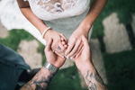 A tattooed husband and wife excchange wedding rings during a garden ceremony.