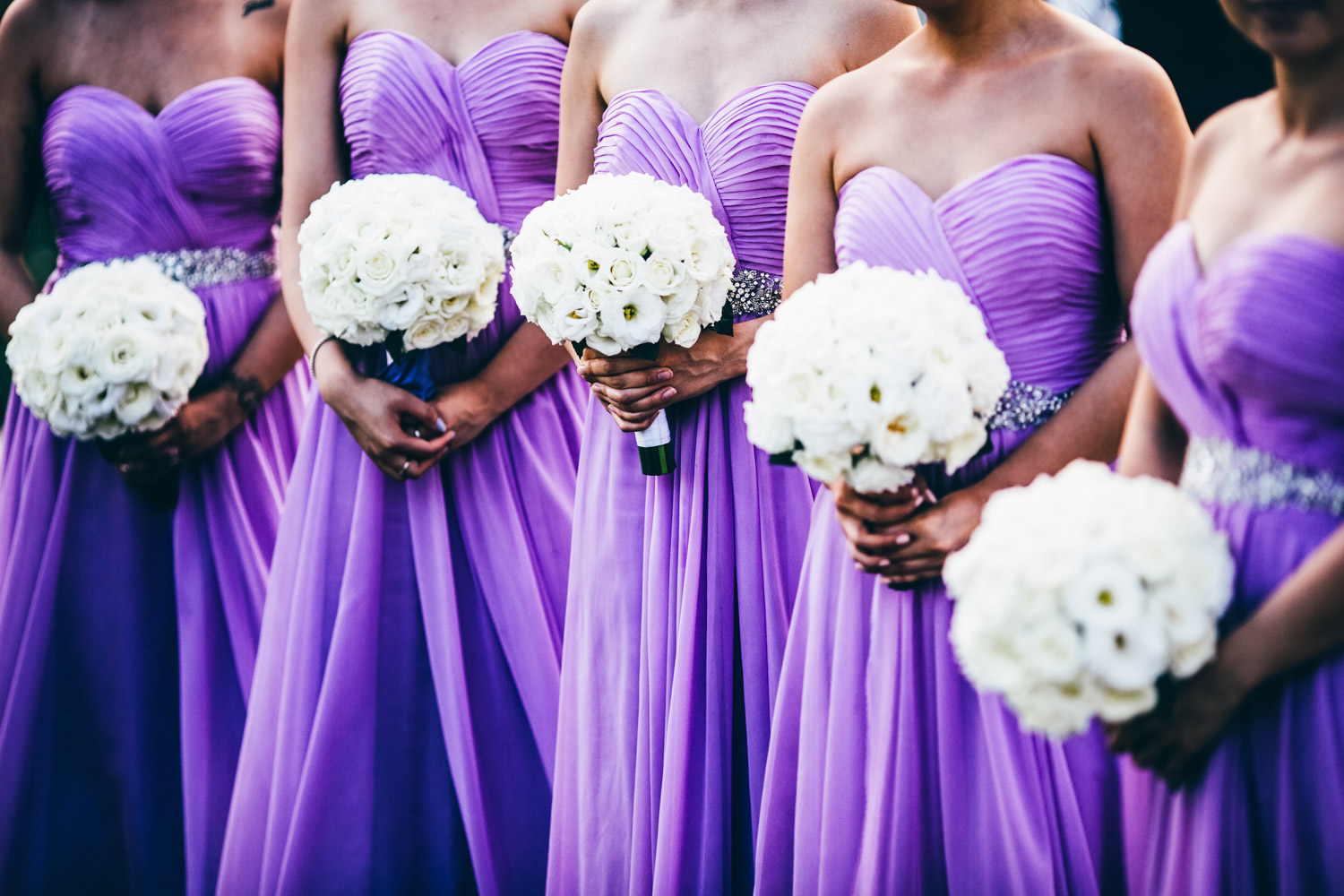 A wedding ceremony with purple dresses and white flowers.