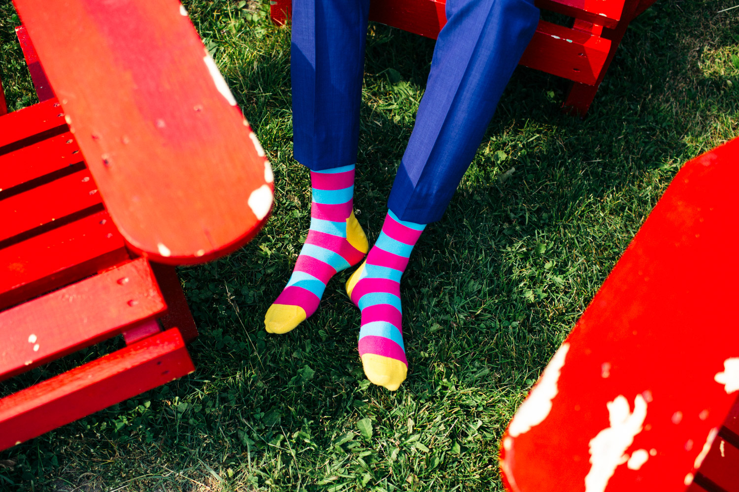 Colorful socks on a grass lawn with red chairs during summer in Nova Scotia, Canada.