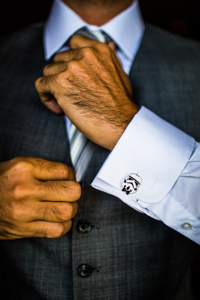 A groom fixes his tie and shows off a Star Wars cufflink.