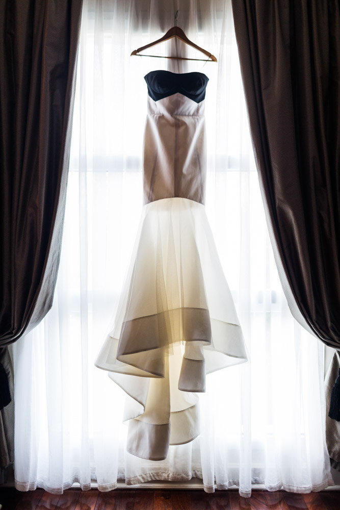 A wedding dress hangs in a window.