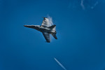 Boeing F/A-18 Hornet building vapor on its wings during flight